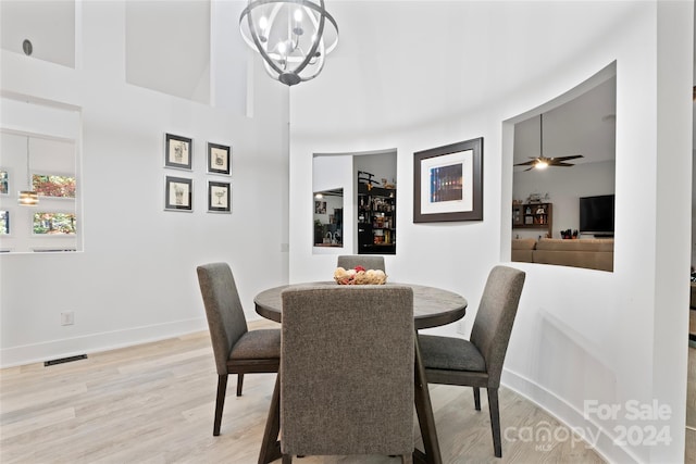 dining space featuring light hardwood / wood-style floors and ceiling fan with notable chandelier