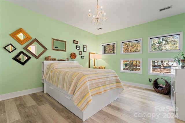 bedroom with light hardwood / wood-style floors and a notable chandelier