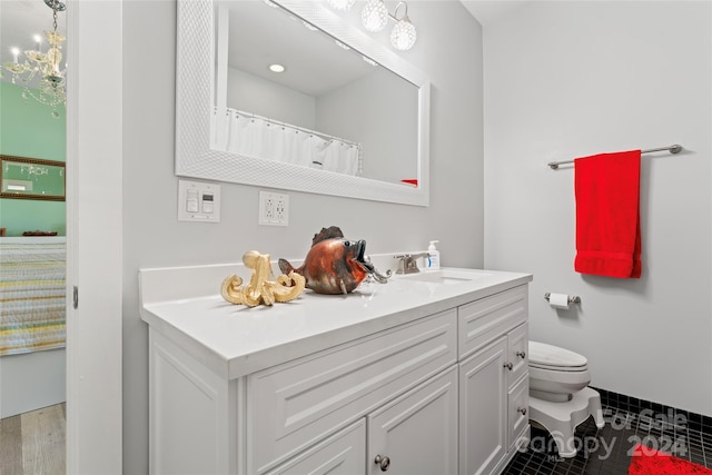 bathroom featuring tile patterned floors, vanity, a notable chandelier, and toilet