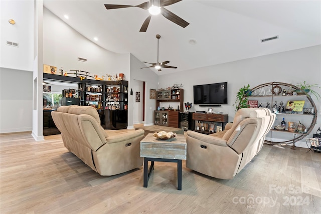 living room featuring bar area, ceiling fan, high vaulted ceiling, and light wood-type flooring