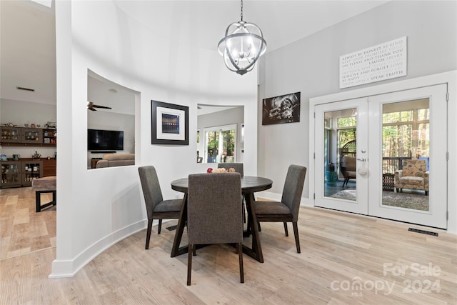 dining room with ceiling fan with notable chandelier, light hardwood / wood-style floors, and french doors