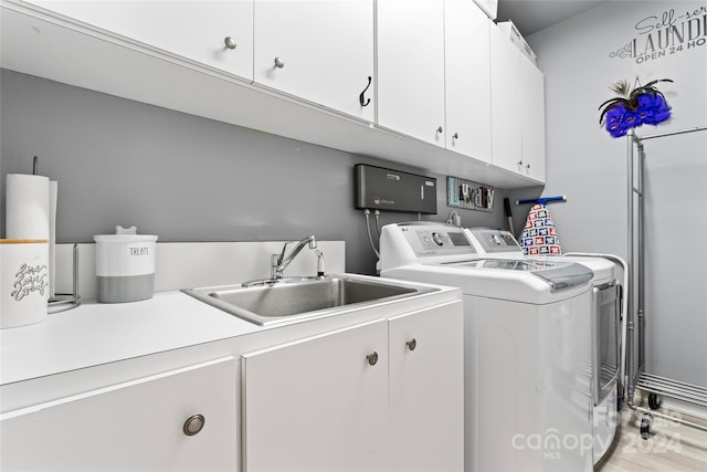 laundry area featuring cabinets, light wood-type flooring, washer and clothes dryer, and sink