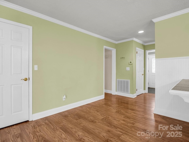 unfurnished room featuring ornamental molding, visible vents, baseboards, and wood finished floors