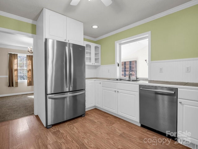 kitchen featuring crown molding, glass insert cabinets, stainless steel appliances, and wood finished floors