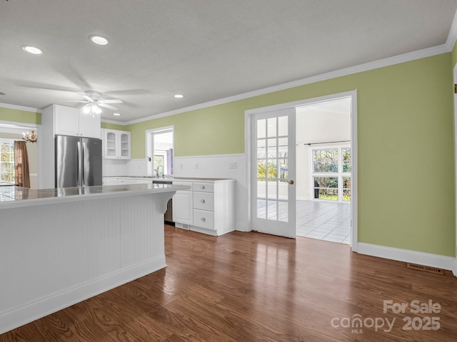 kitchen with dark wood-style floors, crown molding, glass insert cabinets, freestanding refrigerator, and white cabinetry