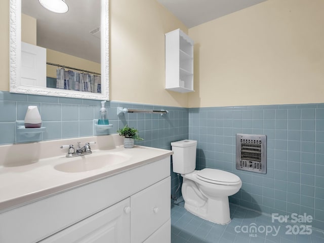 bathroom with toilet, tile patterned floors, tile walls, vanity, and heating unit