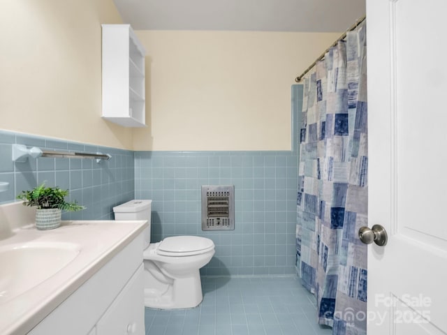 full bath with heating unit, toilet, vanity, tile walls, and tile patterned floors