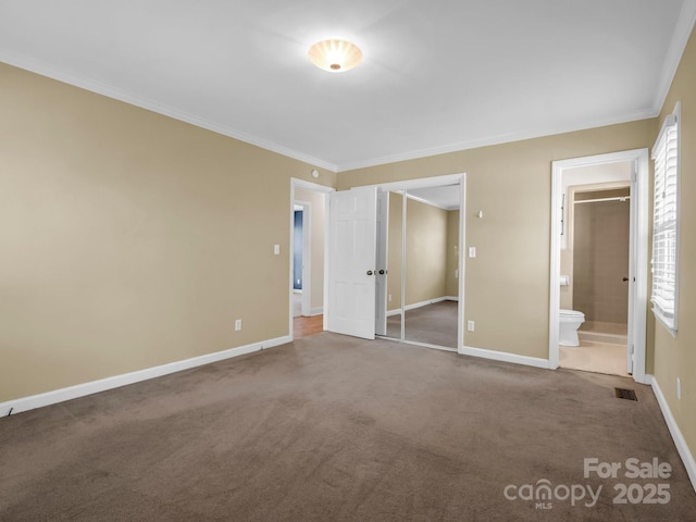 unfurnished bedroom with crown molding, carpet, ensuite bath, and baseboards