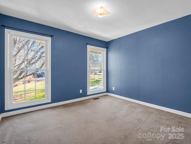 empty room featuring carpet, visible vents, and baseboards