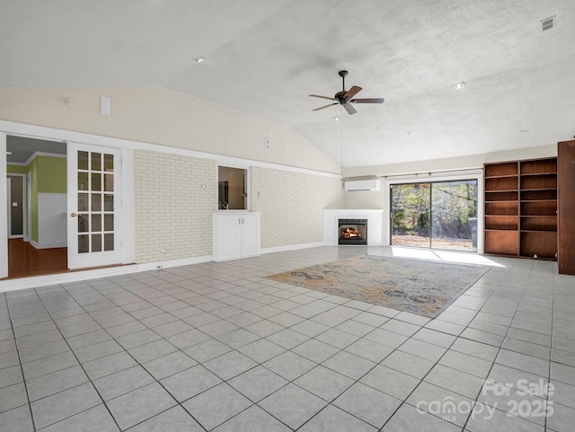 unfurnished living room with a wall unit AC, light tile patterned floors, lofted ceiling, ceiling fan, and a lit fireplace