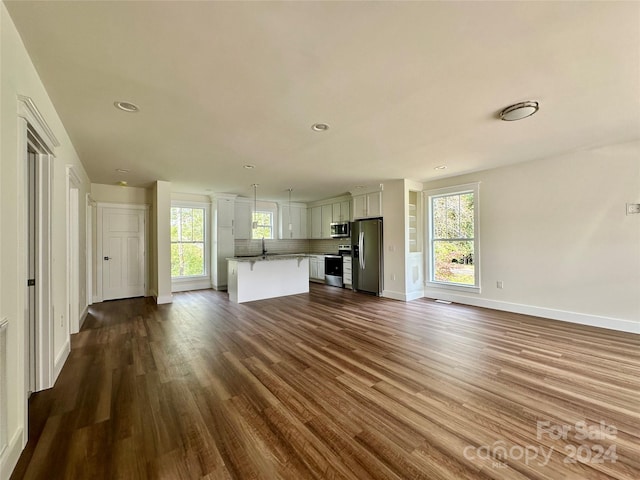 unfurnished living room with dark hardwood / wood-style floors, sink, and a wealth of natural light