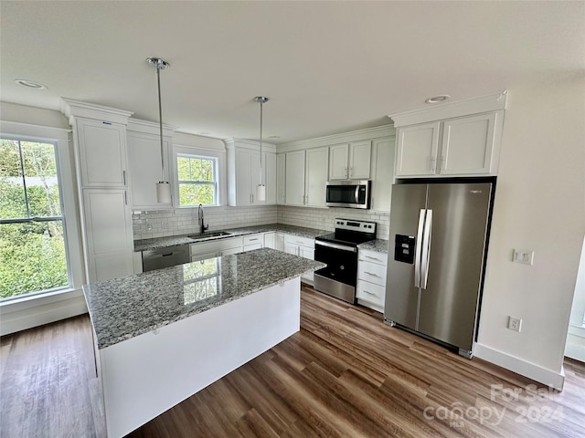 kitchen with dark wood-type flooring, white cabinets, sink, appliances with stainless steel finishes, and decorative light fixtures