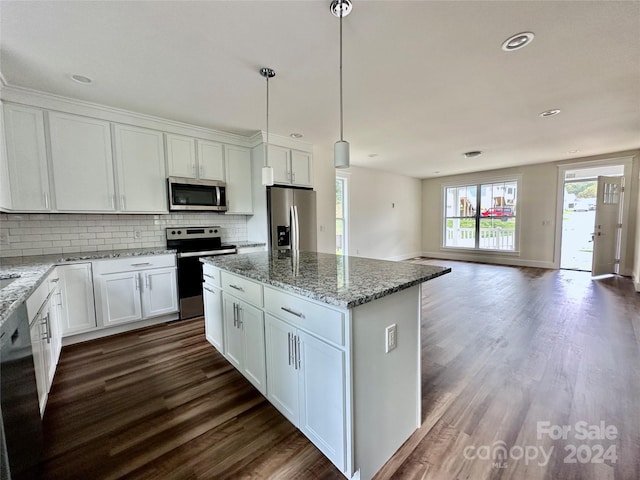 kitchen with white cabinetry, hanging light fixtures, stainless steel appliances, dark hardwood / wood-style floors, and a kitchen island