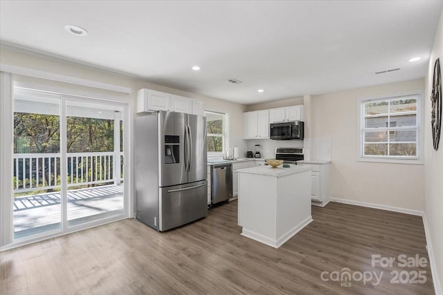 kitchen with white cabinetry, stainless steel appliances, a kitchen island, and a wealth of natural light