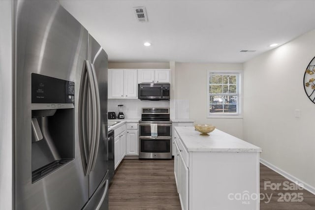 kitchen with white cabinetry, a center island, dark hardwood / wood-style flooring, stainless steel appliances, and backsplash