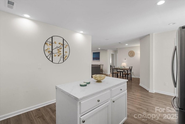 kitchen with a center island, white cabinets, stainless steel refrigerator, and light hardwood / wood-style flooring