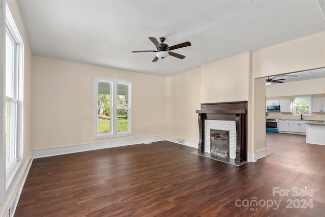 unfurnished living room with a fireplace, dark hardwood / wood-style flooring, a healthy amount of sunlight, and sink