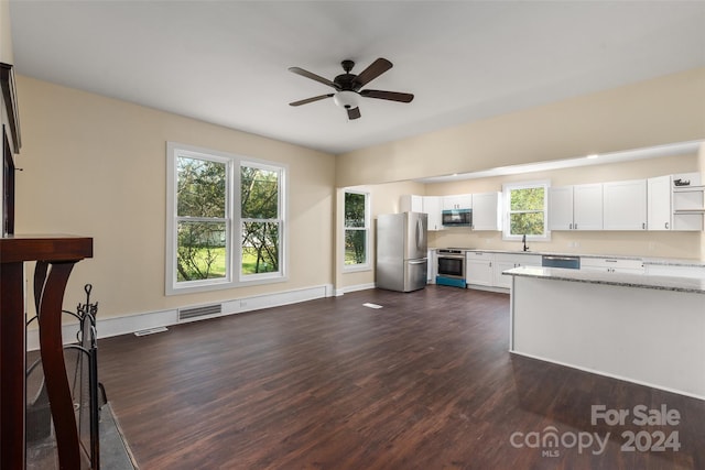 kitchen featuring appliances with stainless steel finishes, light stone counters, sink, dark hardwood / wood-style floors, and white cabinetry