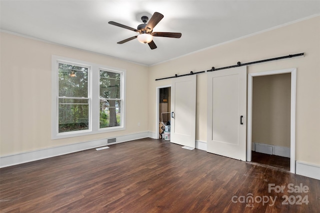 unfurnished bedroom featuring a barn door, crown molding, ceiling fan, and dark wood-type flooring