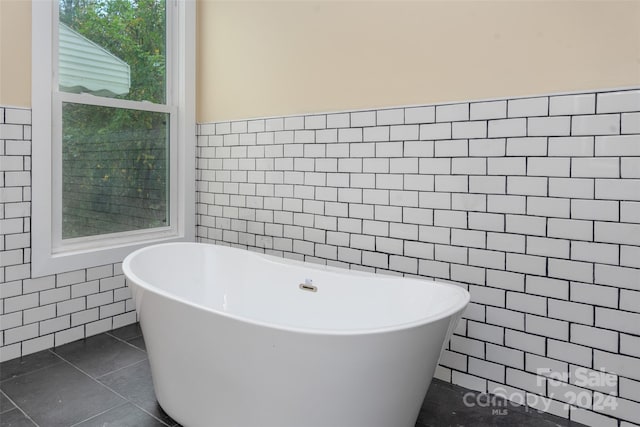 bathroom featuring tile patterned flooring, a bathtub, and tile walls