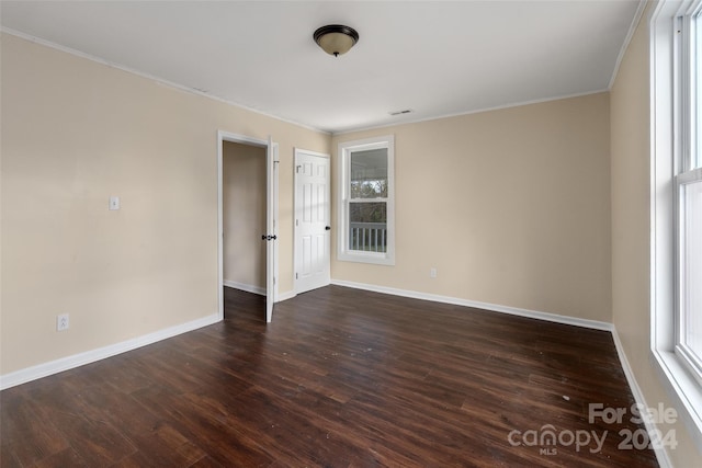 empty room with crown molding and dark wood-type flooring