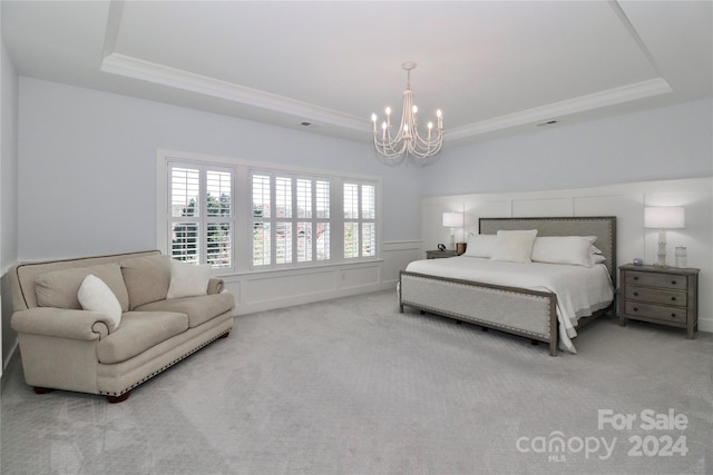 carpeted bedroom featuring a tray ceiling and a notable chandelier