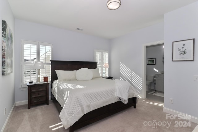 bedroom with light colored carpet and ensuite bath