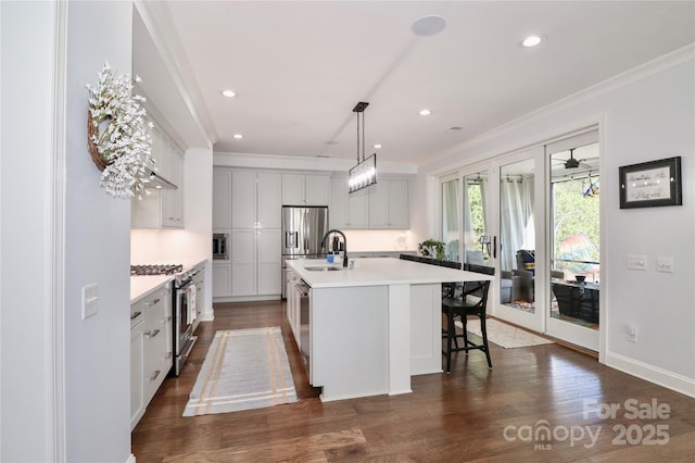 kitchen featuring sink, ornamental molding, appliances with stainless steel finishes, an island with sink, and pendant lighting