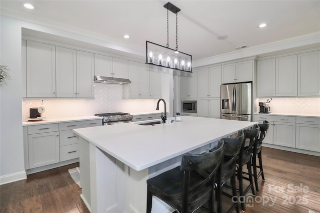 kitchen featuring a breakfast bar, sink, a center island with sink, dark hardwood / wood-style floors, and stainless steel appliances