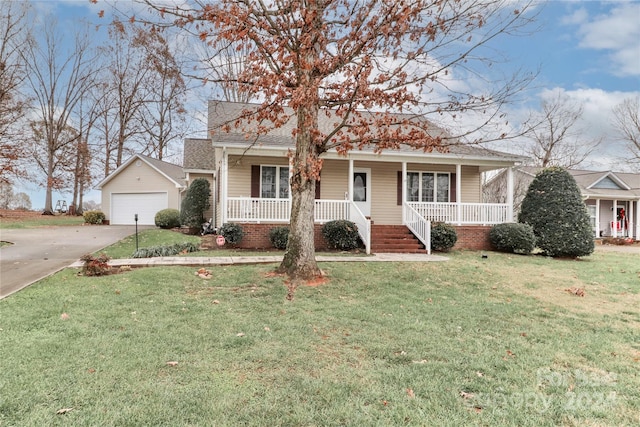 view of front of property featuring a porch, a garage, an outbuilding, and a front lawn