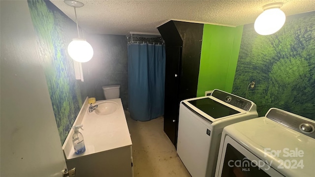 laundry room with a textured ceiling, washing machine and dryer, and sink