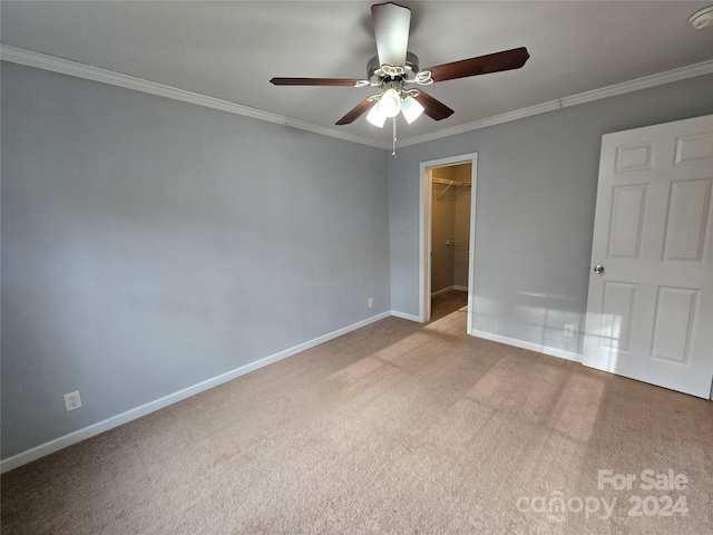 carpeted empty room with ceiling fan and crown molding