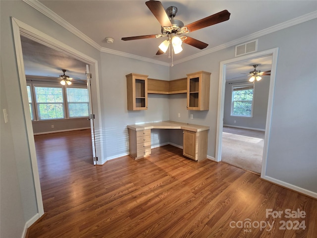 kitchen with a wealth of natural light, light brown cabinets, built in desk, and ornamental molding