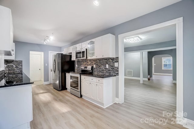 kitchen featuring sink, light wood-type flooring, appliances with stainless steel finishes, tasteful backsplash, and white cabinetry