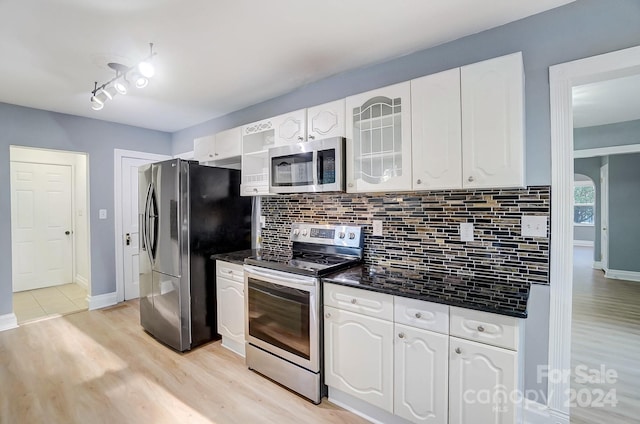 kitchen featuring appliances with stainless steel finishes, backsplash, light hardwood / wood-style flooring, and white cabinetry