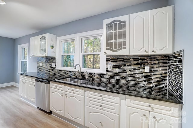 kitchen featuring white cabinets, sink, light hardwood / wood-style flooring, dark stone countertops, and dishwasher