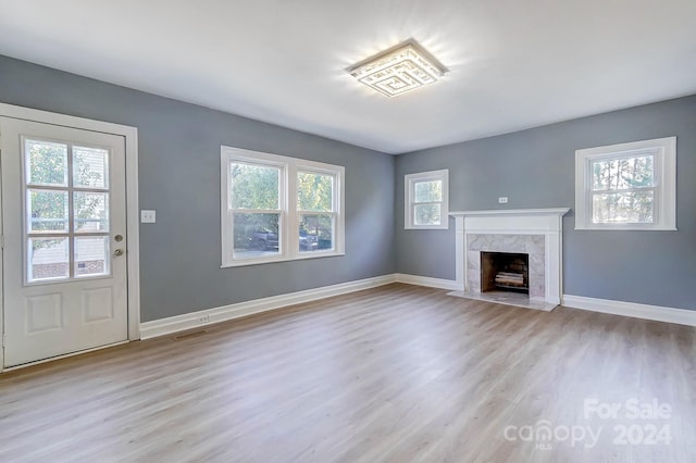 unfurnished living room featuring a high end fireplace and light hardwood / wood-style floors