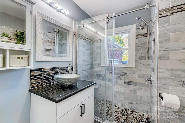 bathroom with vanity, a shower with shower door, and decorative backsplash