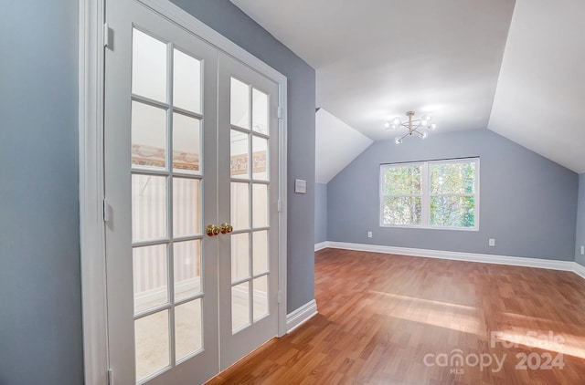 bonus room with an inviting chandelier, lofted ceiling, and light hardwood / wood-style flooring