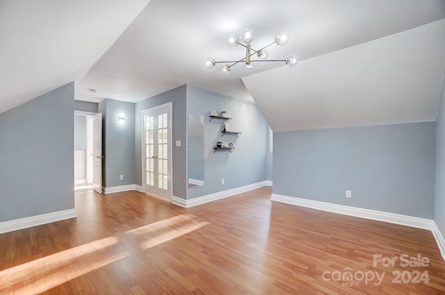 bonus room featuring light hardwood / wood-style floors, lofted ceiling, and a chandelier