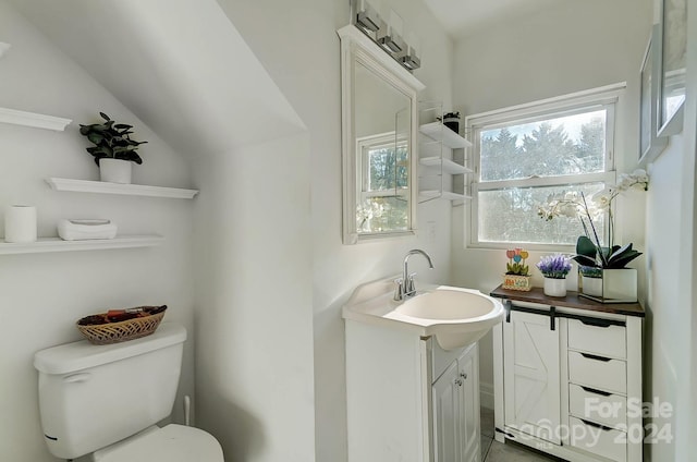 bathroom featuring vanity, toilet, and vaulted ceiling