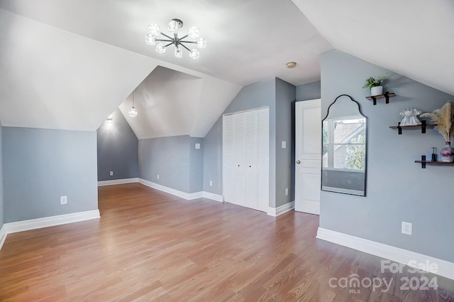 additional living space with light hardwood / wood-style flooring and lofted ceiling