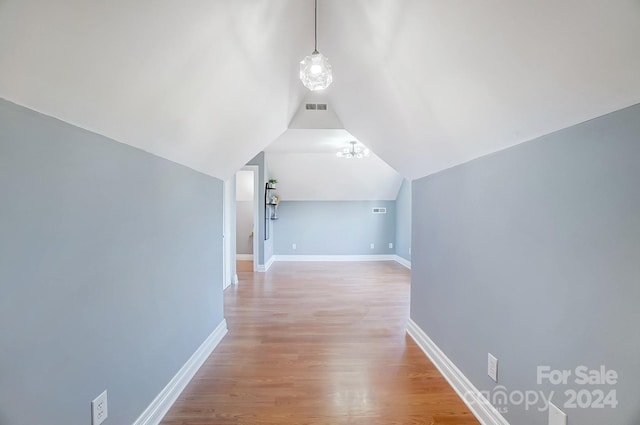 corridor with light wood-type flooring and lofted ceiling