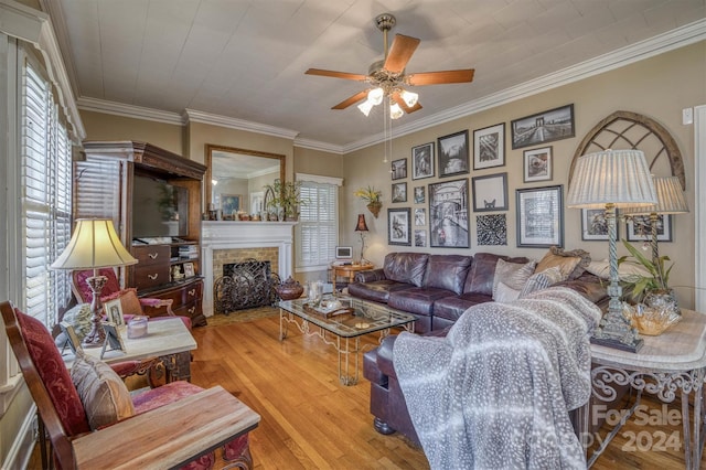 living room featuring a fireplace, light wood-type flooring, ornamental molding, and a wealth of natural light