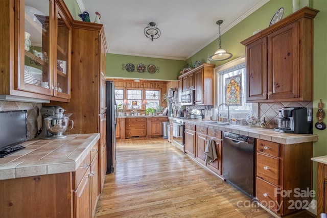 kitchen with tile countertops, a healthy amount of sunlight, hanging light fixtures, and stainless steel appliances