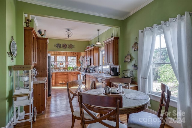 dining area featuring light wood-type flooring, crown molding, and sink