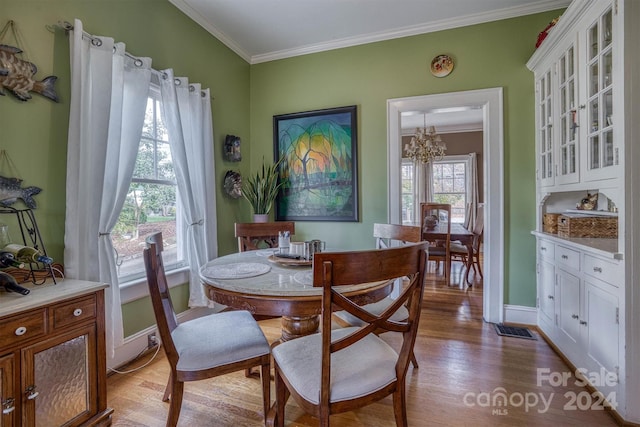 dining space featuring light hardwood / wood-style flooring, ornamental molding, and an inviting chandelier