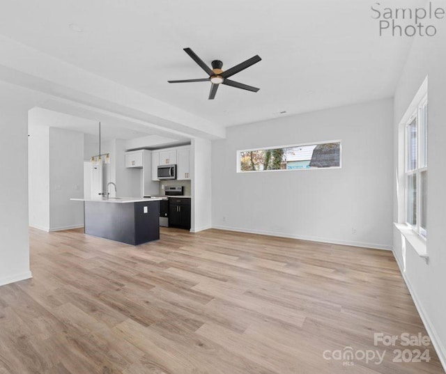 unfurnished living room featuring ceiling fan, light hardwood / wood-style flooring, and sink