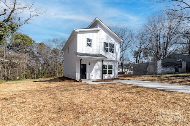 modern inspired farmhouse with a front lawn, board and batten siding, and fence