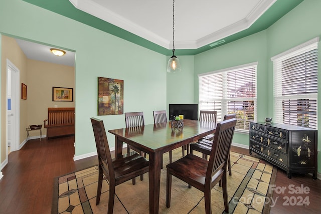 dining area with ornamental molding, a tray ceiling, and dark wood-type flooring